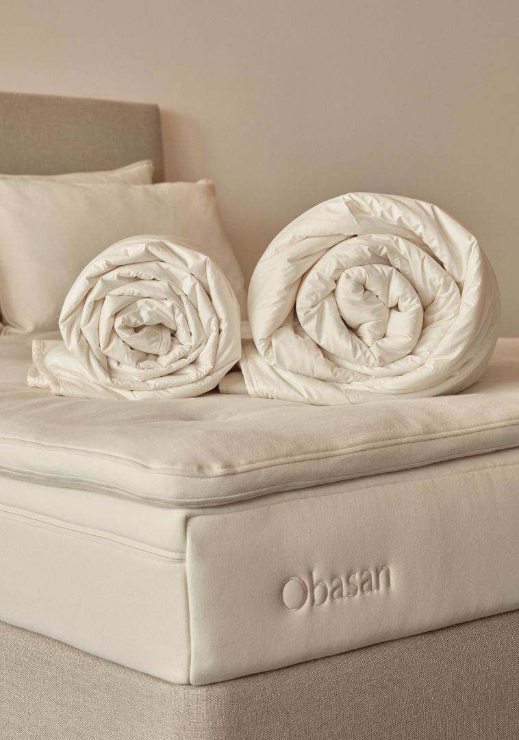 A white comforter laying in a bench